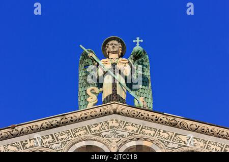 Statue of archangel  Saint Michael atop the gable of the San Michele in Foro Basilica church in Lucca (province of Lucca) in Tuscany, Italy Stock Photo