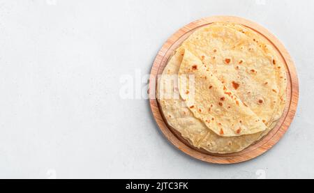 Indian chapati cakes on a wooden board on a gray background. Stock Photo