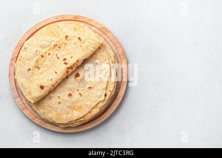 Traditional Indian chapati cakes on a wooden board on a gray background. Stock Photo