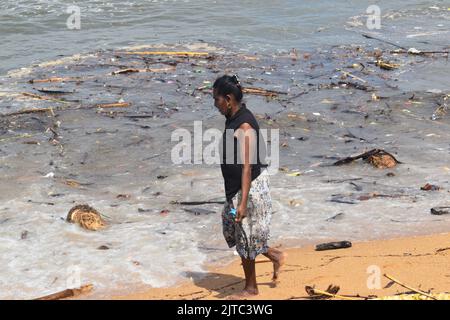 People collecting Wood and plastic wastage which has washed ashore due to rough seas in the Indian ocean in the outskirts of Colombo. They use the wood as firewood for cooking and sell the plastic for recycling purposes. Sri Lanka. Stock Photo