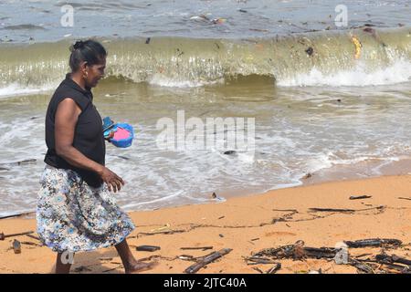 People collecting Wood and plastic wastage which has washed ashore due to rough seas in the Indian ocean in the outskirts of Colombo. They use the wood as firewood for cooking and sell the plastic for recycling purposes. Sri Lanka. Stock Photo