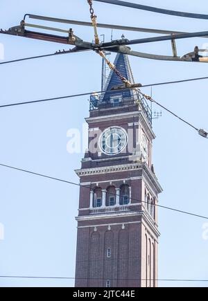 Tall brick tower with clock behind overhead tram and power lines against blue sky in Seattle, Washington USA. Stock Photo