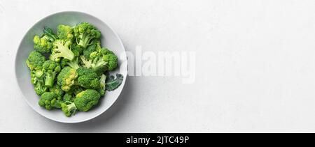 Ripe broccoli sliced in a gray plate on a light background. Healthy food. Stock Photo