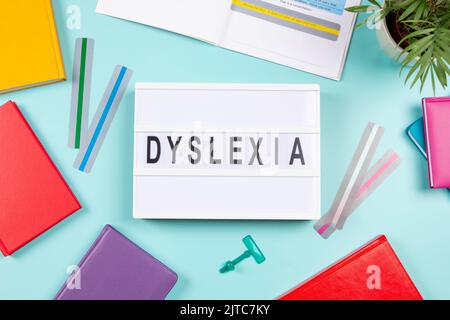 Dyslexia awareness, help children with reading, learning difficulties concept. Lightbox with DYSLEXIA word, colorful books and open book with reading Stock Photo