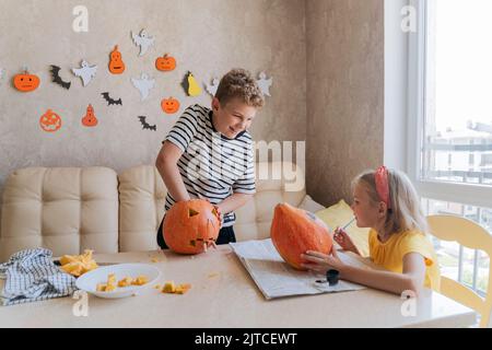 Children are preparing for Halloween, coloring and cutting pumpkins. Stock Photo