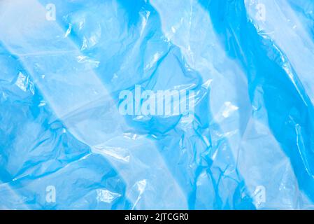 Blue plastic background, striped single use bag. Concepts: sustainability, recycling, pollution. Stock Photo