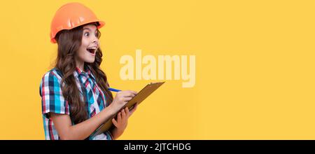Renovation child, surprised teen girl in construction helmet making notes in clipboard, check results. Child builder in helmet horizontal poster Stock Photo