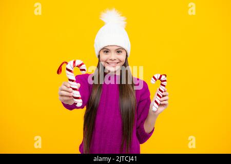Modern teenage girl 12, 13, 14 year old wearing sweater and knitted hat on isolated yellow background. Stock Photo