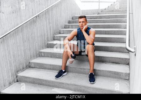 sportsman with shake in bottle sitting on stairs Stock Photo