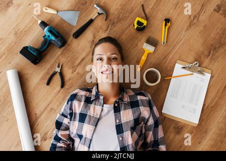 woman with working tools lying on wooden floor Stock Photo