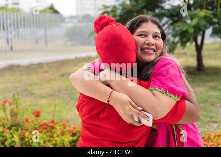 Two indigenous women meet in a city park Stock Photo