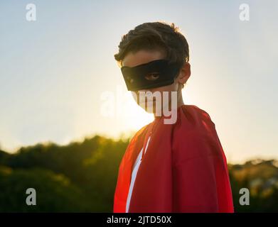 villain better watch out. Portrait of a young boy in a cape and mask playing superhero outside. Stock Photo