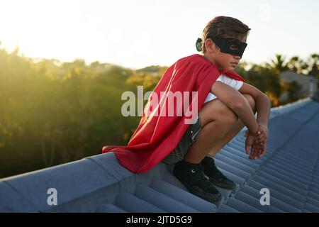 Crime never sleeps and neither does he. a young boy in a cape and mask playing superhero outside. Stock Photo