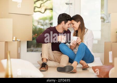 Taking a timeout on moving day. an affectionate young couple taking a coffee break while moving into a new home. Stock Photo