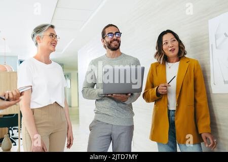 Group of diverse designers smiling cheerfully during a meeting in a creative office. Team of multicultural businesspeople collaborating on a new innov Stock Photo