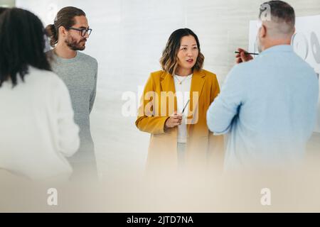 Diverse design professionals sharing innovative ideas during a meeting in a modern office. Team of multicultural businesspeople collaborating on a new Stock Photo