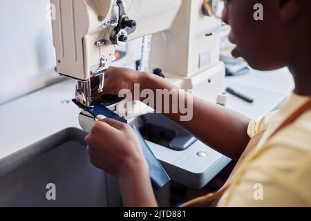 Close up of black young woman using sewing machine while designing handmade leather bag Stock Photo