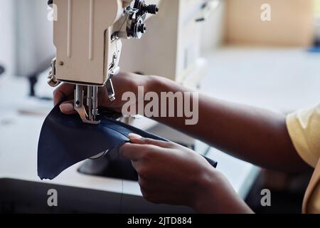 Side view close up of black young woman using sewing machine and creating handmade leather bag, copy space Stock Photo