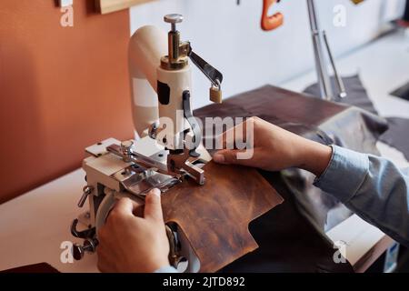 Close up of woman sewing handmade leather bag in workshop, copy space Stock Photo