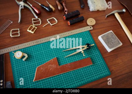 Leatherworking station with various tools on wooden table, copy space Stock Photo