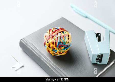 Colorful rubber band ball, stapler and notebook on white background, closeup Stock Photo
