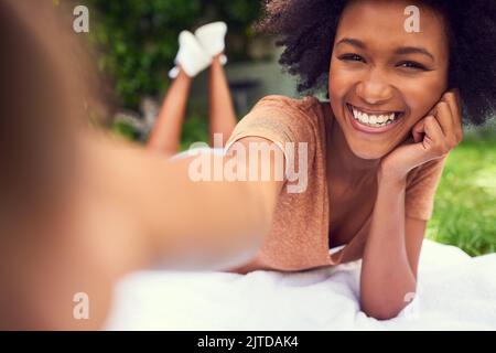 Natures makes for the best selfies. a young woman taking a selfie white at the park. Stock Photo