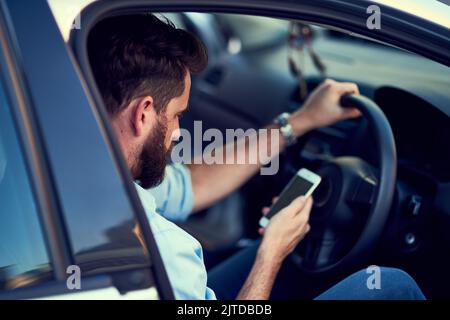 This looks easy enough to find. a unrecognizable man using his phone while driving to a destination. Stock Photo