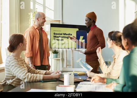 Portrait of creative team meeting in office with focus on black man giving marketing presentation Stock Photo