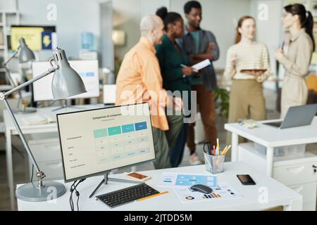 Background image of computer screen with data on workplace and blurred business team in office, copy space Stock Photo