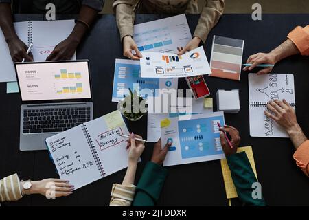 Top down view at table with documents and diverse team discussing marketing data Stock Photo