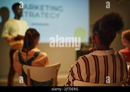 Back view of young black woman listening to business coach while sitting in audience in training class, copy space Stock Photo