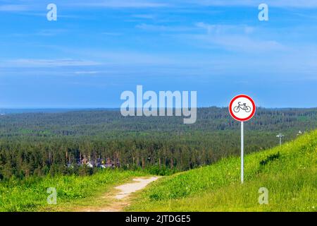 Round prohibition road sign No bikes mounted near rural trail going down the hill Stock Photo