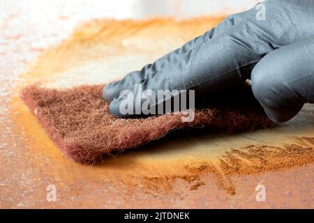 Rubbing rust off sheet steel with an abrasive pad. Restoration project ...