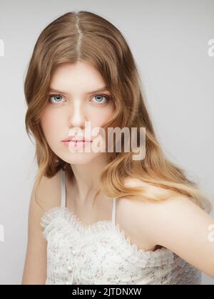 One young woman looking at camera. Vertical studio portrait of young charming girl. Stock Photo