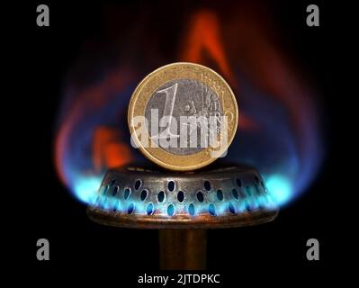 Close up of a one euro coin on top of a blue flame gas burner, concept imgage showing rising gas prices Stock Photo