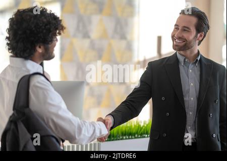 Young manager welcoming new employee and looking positive Stock Photo