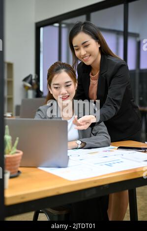 Kind and professional Asian businesswoman or female manager giving an advice to her newest female employee's work. teamwork concept Stock Photo