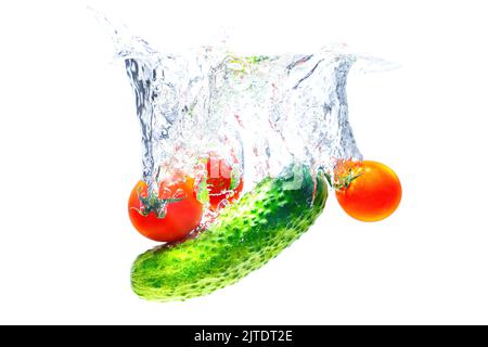 Cherry tomatoes and fresh cucumber dropped in water with splashes isolated on white background. Stock Photo