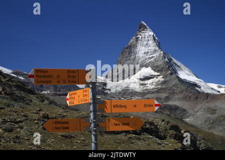 A closeup of a hiking trail sign post with the alpine Matterhorn on the background Stock Photo