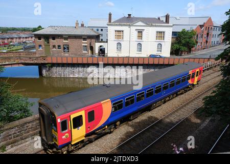 A brightly coloured train on a track by the river Dee in Chester. Stock Photo