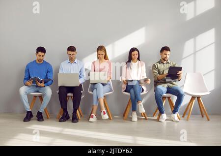 Young people using laptops and tablets while waiting for job interviews or business appointments Stock Photo