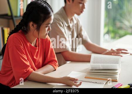 School children sitting at school desk and reading book for English class Stock Photo