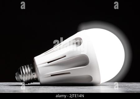 Glowing LED bulb light on the grey table on black background Stock Photo