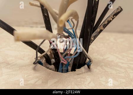 old electrical wires are sticking out of the mounting box in the wall Stock Photo