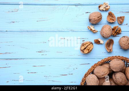 Walnuts kernels in basket on blue wooden background. Walnuts kernels on blue wooden table Stock Photo