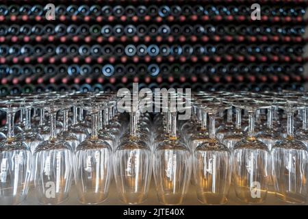 Empty wine glasses with many  stacked bottles as a background - preparation to wine tasting in the winery of Lanzarote, Spain Stock Photo