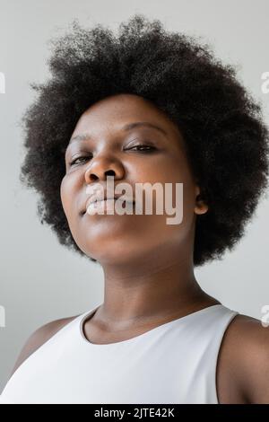 low angle view of confident african american plus size woman in sportswear isolated on grey,stock image Stock Photo