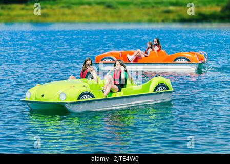 Two pedal boats on a mountain lake with teenagers Stock Photo