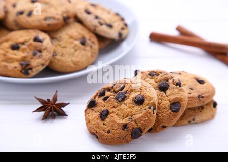 Chocolate chip cookies on plate on white wooden table. Chocolate cookies and cinnamon sticks. Stock Photo