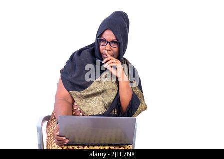 beautiful muslim businesswoman sitting on white background working on laptop with thinking gesture. Stock Photo